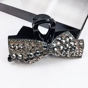 Detailed view of black bow hair claw clip with shimmering dark grey rhinestones