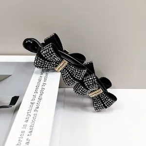 Detail of black fabric bow hair clip with sparkling silver rhinestones and gold metal tag