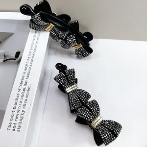 Macro detail of elegant black layered bow banana clip with sparkling dark rhinestones