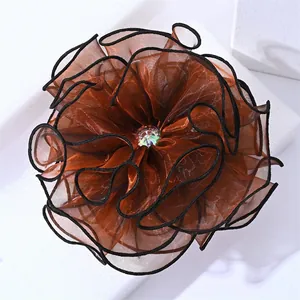 Macro d'une grande pince à cheveux fleur en organza orange avec centre en strass brillant