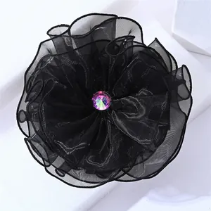 Gros plan sur une élégante pince à cheveux fleur en mousseline noire avec strass brillant