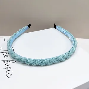 Detalle macro de la diadema trenzada de cuentas azul claro con capa protectora interna