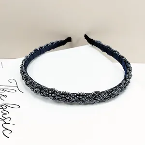 Detalle de diadema trenzada con cuentas negras con textura en espiral y acabado brillante