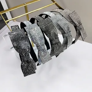 Detail view of five colors of rhinestone bow headbands on a golden metal display rack