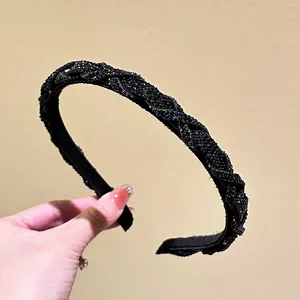 Close-up of black braided rhinestone headband with twisted design and sparkling crystal beads