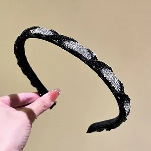 Close-up of elegant braided headband with sparkling silver rhinestones on black fabric