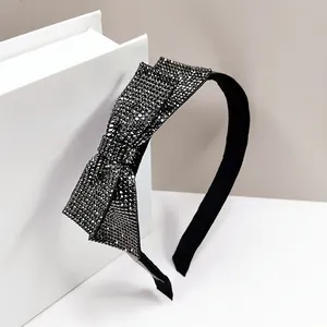 Detail of elegant black wide headband with large shimmering dark grey rhinestone bow