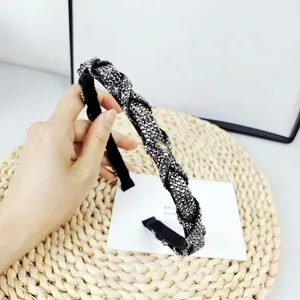 Close-up of twisted rhinestone headband with grey crystals on black fabric base