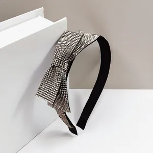 Detail of a black headband featuring a large bow fully embellished with silver rhinestones