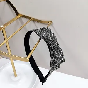 Detailed close-up of a black rhinestone headband with a sparkling crystal bow on a gold stand