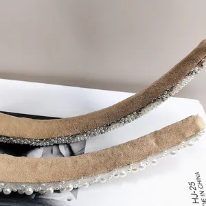 Détail du serre-tête en velours kaki orné de perles blanches et de strass brillants