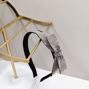 Close-up of a black headband featuring a stylish bow encrusted with silver rhinestones