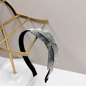 Close-up of sparkling rhinestone bow headband with crystals on a black fabric base