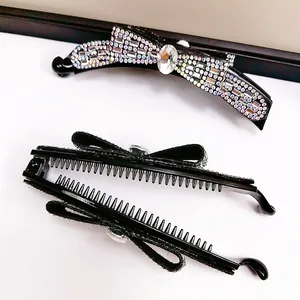 Detail einer schwarzen Schleifen-Haarspange mit bunten Kristallen und ovalem Strass