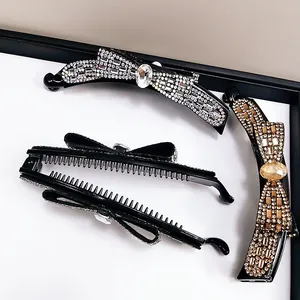 Makroaufnahme von drei Kristall-Schleifen-Bananenklammern mit Strass in Schwarz und Gold