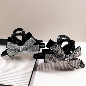 Détail de pinces à cheveux noires élégantes avec strass brillants en forme de nœud