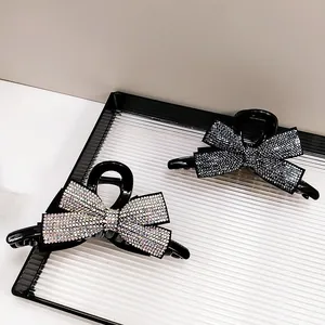 Détail de deux pinces à cheveux noeud avec strass multicolores et noirs pour coiffure chic