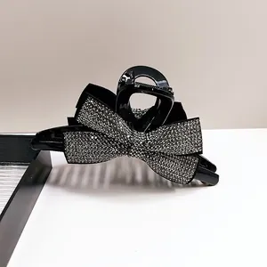 Gros plan d'une grande pince à cheveux noire avec des nœuds en strass brillants