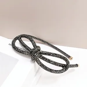 Macro detail of black rhinestone headband with fixed bow and elegant gold metal end caps