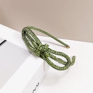 Macro shot of green rhinestone bow headband with elegant gold metal end caps detail