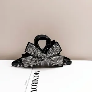 Détail de la pince à cheveux noeud noir avec strass argentés posée sur un magazine de mode