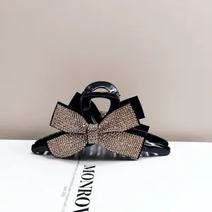 Détail d'une pince à cheveux noire avec un nœud serti de strass brillants élégants