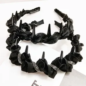 Gothic black satin wave headband with spikes and rhinestones on white background