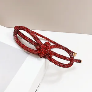 Detailed close-up of a red rhinestone knotted headband with premium gold metal ends
