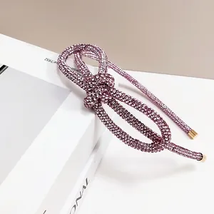 Macro detail of a knotted purple rhinestone headband with shimmering crystals and gold ends