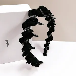 Detail of black pleated headband featuring rows of silver rhinestones and interior plastic teeth