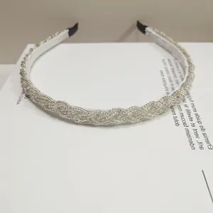Detalle de diadema trenzada plateada decorada con finas cuentas blancas y artesanales