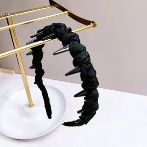 Detail of black punk wavy headband with sharp spikes and pleated texture on a gold stand