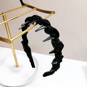 Detail of a black fabric headband with silver metal spikes on a luxury gold stand