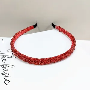 Detalle de la diadema trenzada de cuentas rojas con textura retorcida y puntas de tela negra