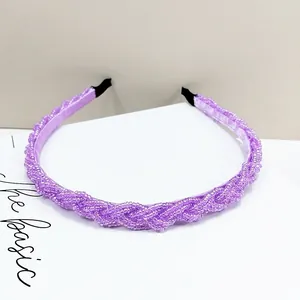 Detalle de diadema trenzada con cuentas moradas mostrando la textura tejida y el acabado