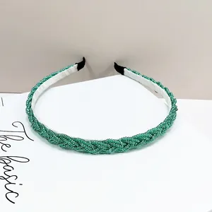 Detalle de diadema trenzada con cuentas verdes de diseño artesanal y forro interior