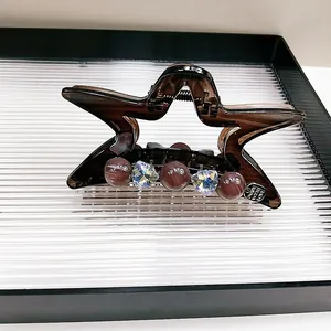 Dettaglio della pinza per capelli a stella in resina caffè con perline e strass lucidi