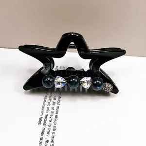 Dettaglio molletta a stella nera con perline blu e cristalli a forma di cuore