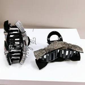 Close-up of black bow hair claw clips with shimmering rhinestones and strong springs