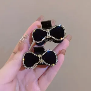 Detalle de pequeñas pinzas para el pelo con lazo negro y diamantes de imitación