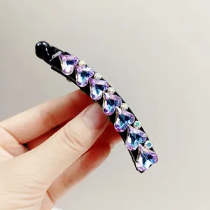 Detailed close-up of heart-shaped purple crystals on a stylish black banana hair clip