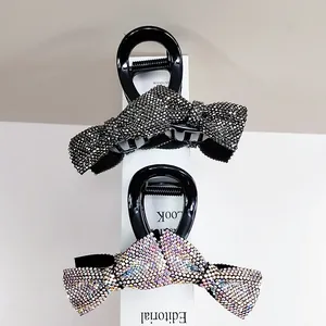 Detailed view of two bow hair clips with dark grey and iridescent rhinestones