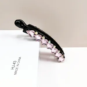 Detail of banana hair clip featuring pink heart crystals and iridescent rhinestones