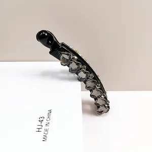 Close-up of heart-shaped grey crystals on a black banana hair clip with gold metal claws
