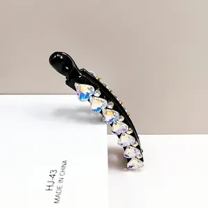 Detail of banana hair clip featuring colorful heart-shaped K9 crystals on black resin