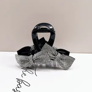Close-up of sparkling rhinestone bow hair claw clip with black glossy finish
