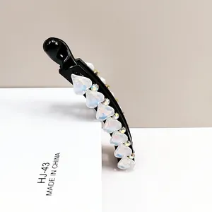 Detail view of a black banana clip with heart shaped crystals and sparkling rhinestones