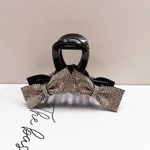 Macro detail of a sparkling bow hair claw clip with champagne rhinestones on black