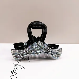 Close-up of a black hair claw clip featuring a large bow set with colorful rhinestones
