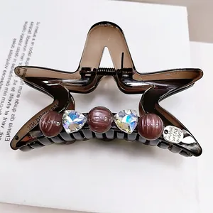 Dettaglio della molletta a stella con perline, cristalli e ciondolo in metallo inciso